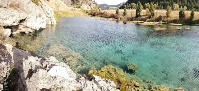 turquoise water lake in a forested valley setting at nimrod hot springs montana