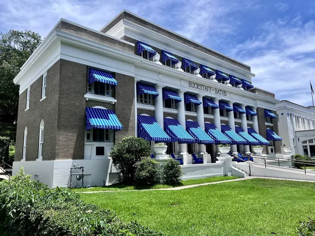 Historic Buckstaff Bathhouse building with large white columns, one side surrounded by green grass and bushes in Hot Springs Arkansas.