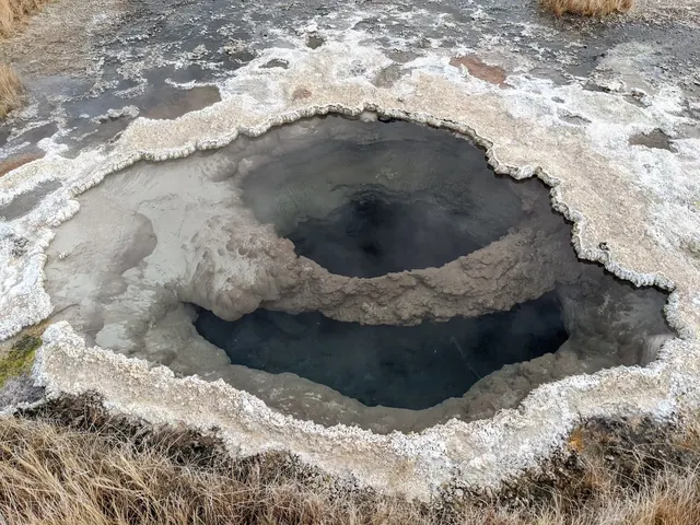 A hot spring vent pool with mineral deposits around its edges bubbling with steam at Borax Hot Springs near Fields, Oregon.