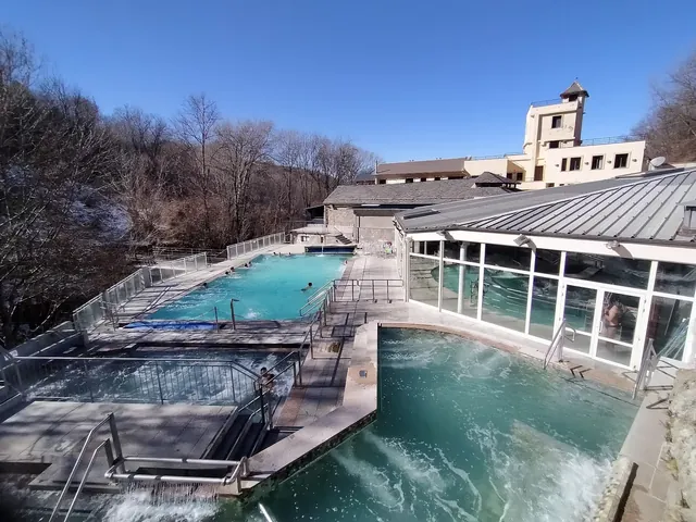Rectangular outdoor mineral pools at Les Bains de Llo in Font-Romeu-Odeillo-Via with railings and clear blue water on a sunny winter day.