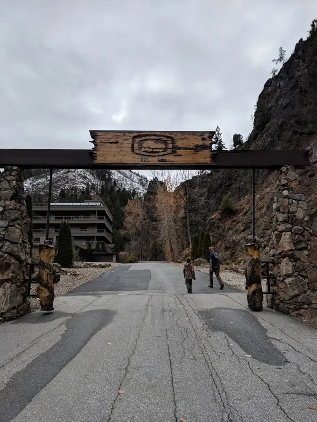 Wooden entrance sign gate with carved bear statues welcomes visitors to Sleeping Child Hot Springs in Hamilton Montana.