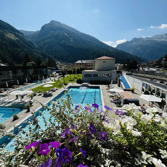 Outdoor hot spring pool at Felsentherme Bad Gastein with clear water, lounge chairs, umbrellas, and mountains in Bad Gastein, Austria.