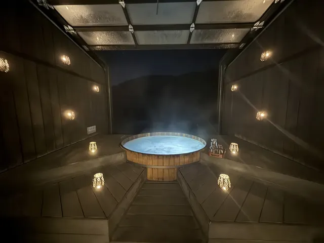 Indoor Onsen Hot Pools wooden hot spring pool with soft lighting and steam at night in Queenstown New Zealand.