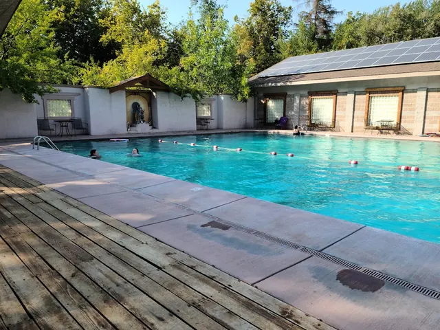 Large outdoor thermal pool at Jackson Wellsprings with blue water, surrounded by chairs and a wooden deck near Ashland Oregon.