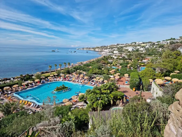 Outdoor hot spring pool at Giardini Poseidon Terme in Forio Ischia Italy with bright blue water and umbrellas near the sea shore.