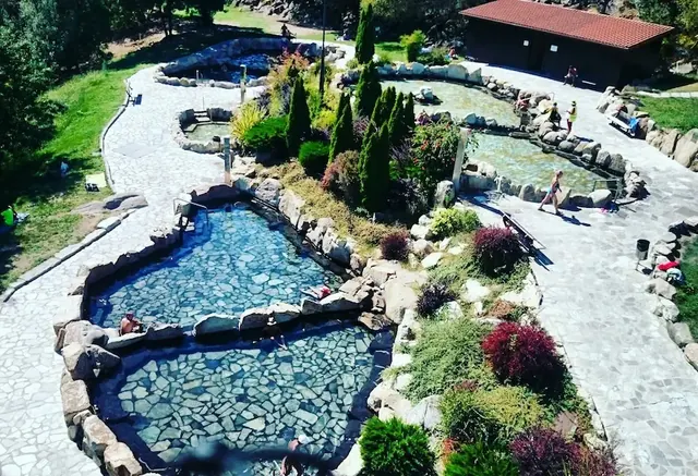 People soaking at outdoor developed hot spring pools surrounded by paved paths at termas de outariz in spain