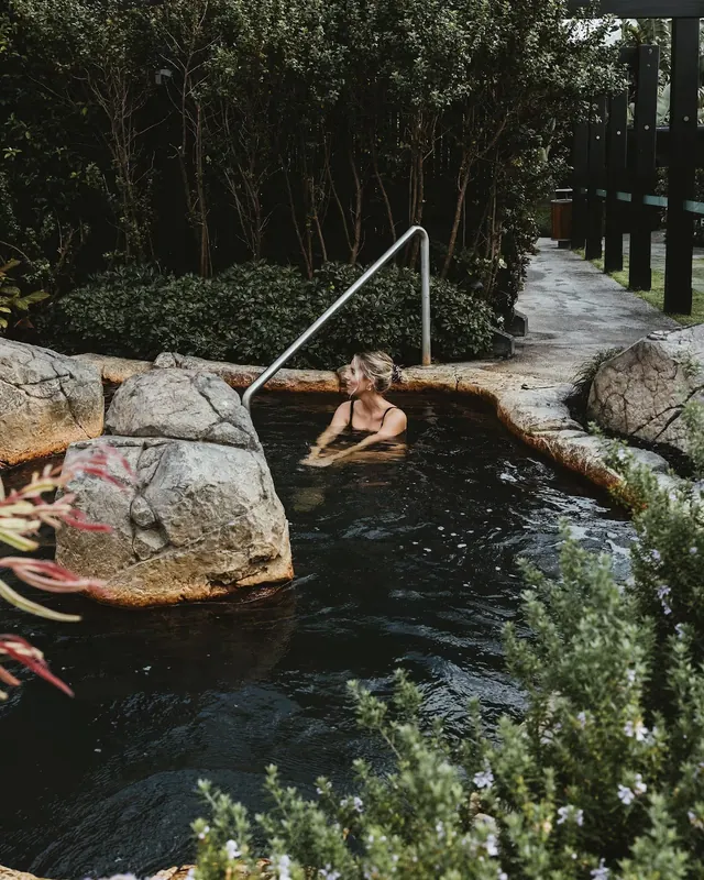 Natural stone soaking pool surrounded by green plants at Deep Blue Hot Springs near Warrnambool on the Great Ocean Road in Australia.