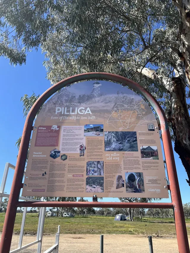 Information board welcoming visitors to Pilliga, highlighting the artesian bore baths and nearby attractions under a clear blue sky.