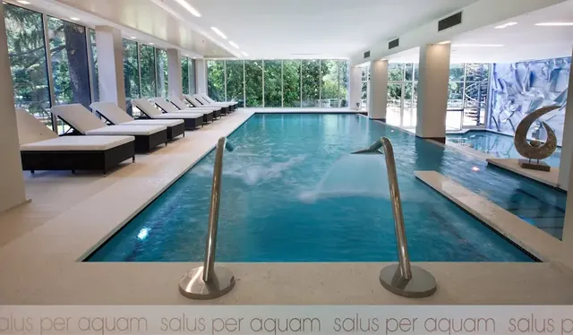 Indoor thermal pool surrounded by big windows and loungers at terme di boario in italy
