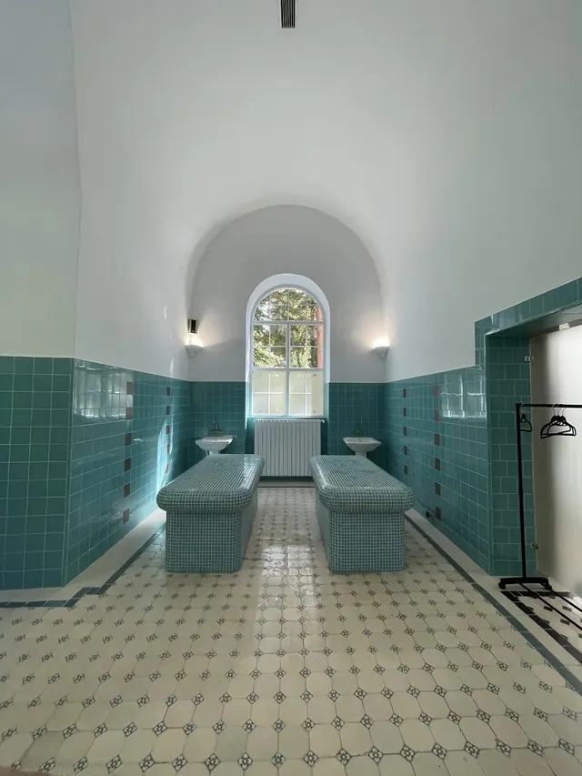 Spacious spa treatment room with teal mosaic benches, patterned floor tiles, and an arched window letting in natural light at Bankya Bulgar.