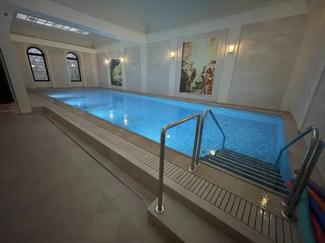 Wide angle view of Windsor SPA Hotel indoor mineral pool showing water reflections and arched windows in Karlovy Vary.