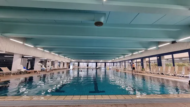 Indoor pool with calm water and numerous lounge chairs along the sides at Interhotel Sandanski Thermal Pools in Sandanski, Bulgaria.