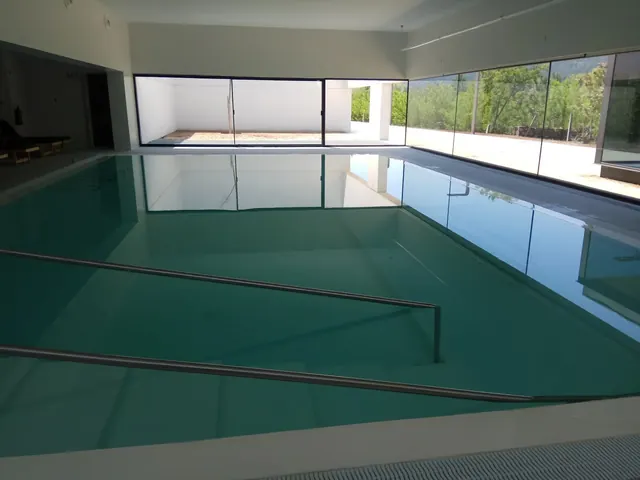 Indoor soaking pool with clear water and metal handrails at Balneario Pedagogico de Vidago in Vidago, Portugal.