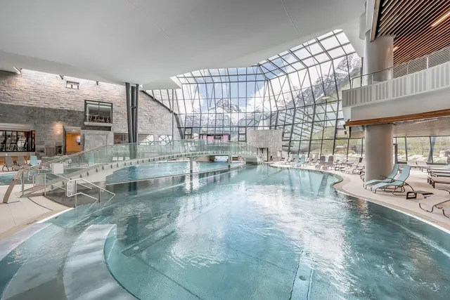 Indoor spa pool at Aqua Dome Tirol Therme with large glass walls offering a clear view of snowy mountain peaks near Langenfeld, Austria.