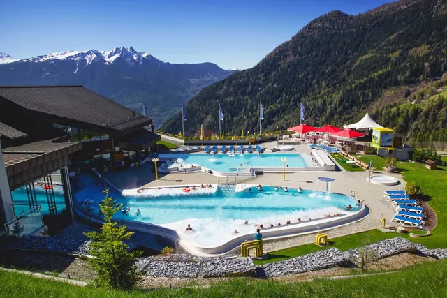 Outdoor hot spring pool area at Les Bains d'Ovronnaz with lounge chairs and mountain views near Martigny, Switzerland.