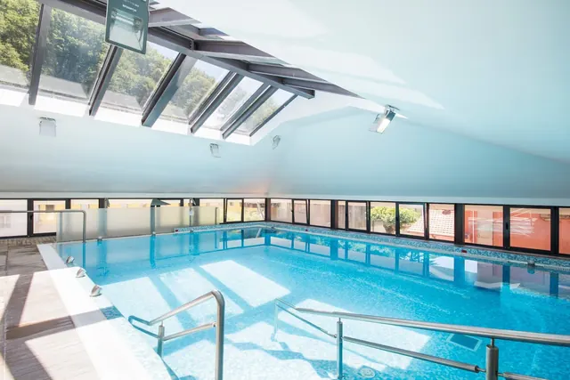 Indoor hot spring pool with handrails and large windows letting in natural light at Termas do Geres near Geres Portugal.