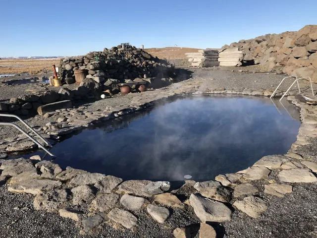 Steaming outdoor hot spring pool surrounded by stone walls at Grettislaug Hot Springs near Saudarkrokur Iceland.