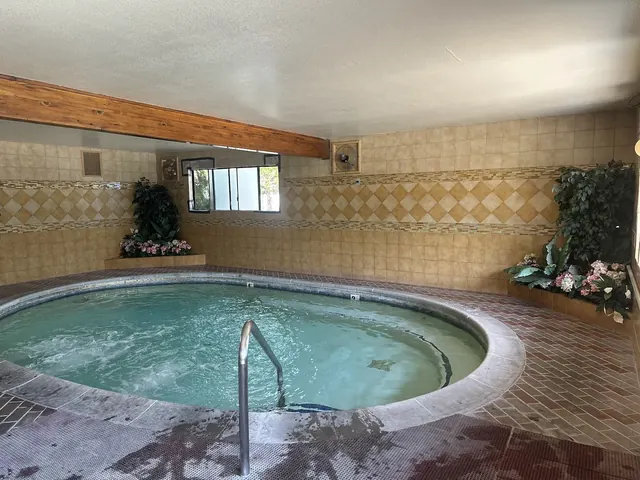 Indoor circular hot spring pool with bubbling water, tiled walls, and decorative plants inside Roman Spa Hot Springs Resort in Calistoga Ca.