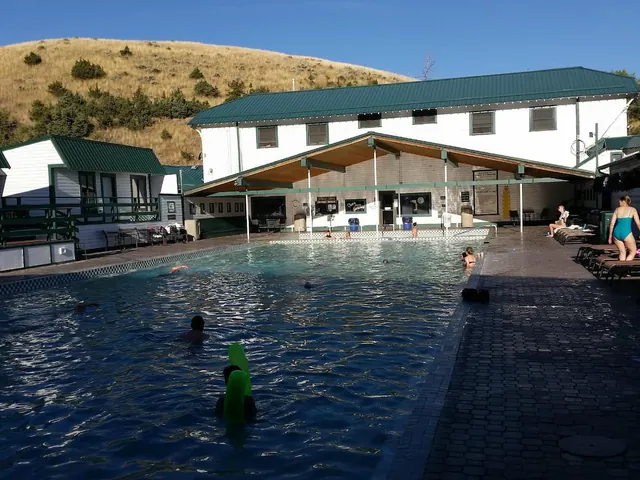 people soaking at outdoor hot spring pools with resort and hills in the background at chico hot springs montana