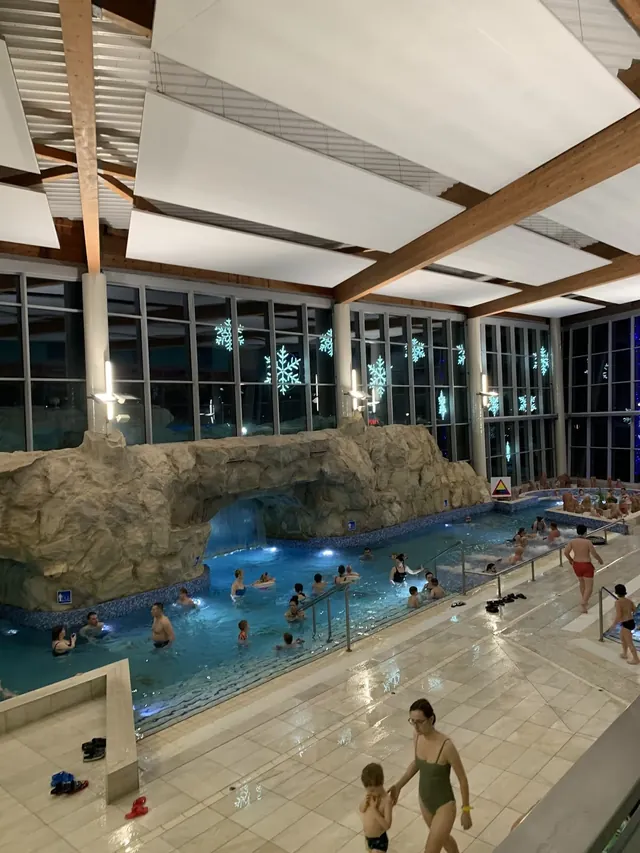 Indoor soaking pool at Termy Uniejow in Uniejow Poland with people relaxing beneath high ceilings and windows decorated with snowflake deca.
