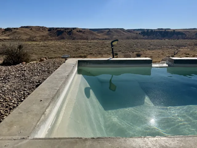 Close-up of sparkling water in the rectangular pool at Desert Reef Hot Springs, surrounded by rocky ground and expansive dry hills near Florence, Colorado.