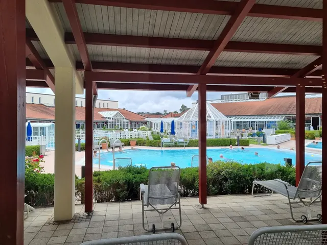 Outdoor spa pool terrace at Limes-Therme Bad Goegging showing loungers and guests enjoying the clear water and sunny weather in Germany.