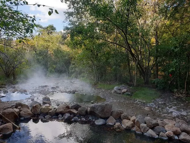 Natural hot spring pools with gently steaming water nestled among rocks and forest near Pai city in Nan province, Thailand.