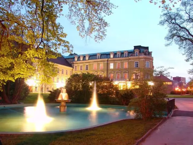 outdoor hot spring pool with illuminated water fountains in front of historical building during dusk in teplice czechia.