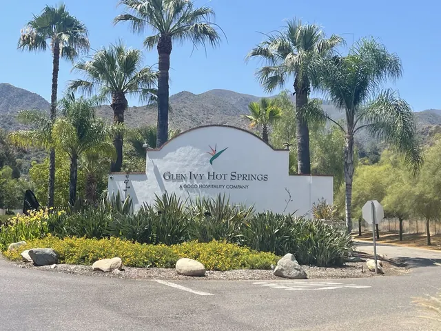 Entrance sign for Glen Ivy Hot Springs in Temescal Valley California with landscaping and palm trees against a backdrop of hills.