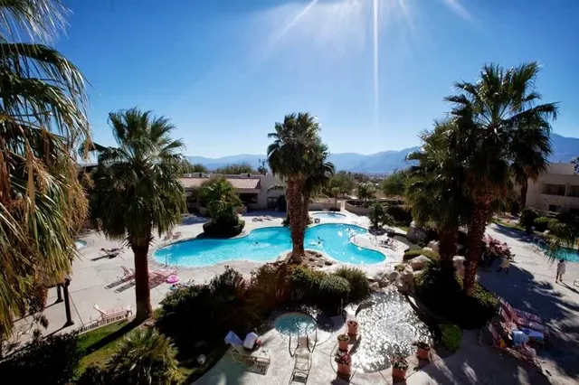 Aerial view of mineral soaking pools and palm trees at Miracle Springs Resort with desert mountains in the background near Desert Hot Sprin.