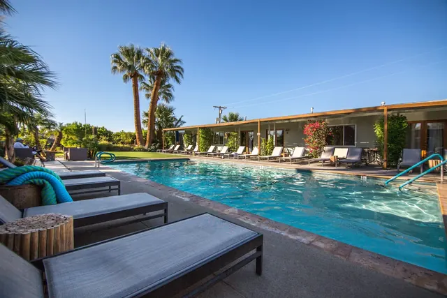 The Spring Resort & Spa outdoor pool flanked by lounge chairs and a single story building with desert landscaping in Desert Hot Springs Cal.