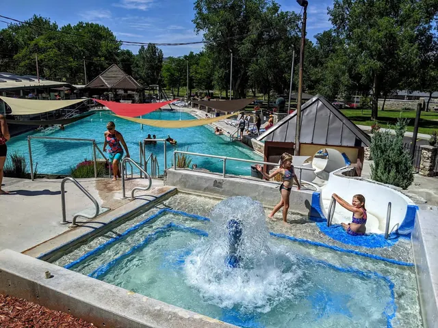 Children play near water features including a bubbling fountain and a slide by the outdoor mineral pool at Star Plunge in Thermopolis Wyomi.