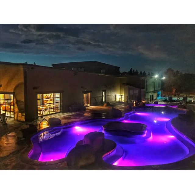 Night view of Broadwater Hot Springs outdoor pool lit with purple lights beside the building near Helena Montana.