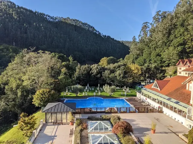 Outdoor inner courtyard of grand hotel with outdoor pool and mountains in the background at balneario de puente viesgo in spain