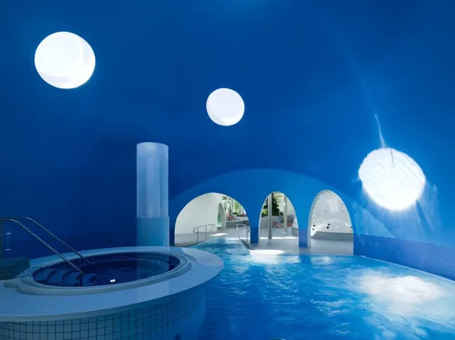 Indoor hot spring pool under a large blue dome with round skylights and archways at Therme Bad Aibling in Bad Aibling, Germany.