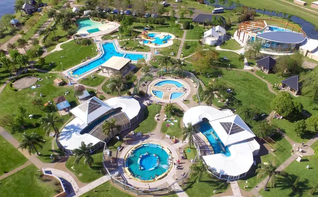 Aerial view of Termas Villa Elisa resort showing multiple pools, green lawns, and walking paths near Villa Elisa, Argentina.