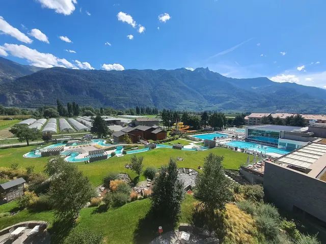 Outdoor spa pools with crystal clear water at Bains de Saillon surrounded by green grass and mountains near Martigny Switzerland.