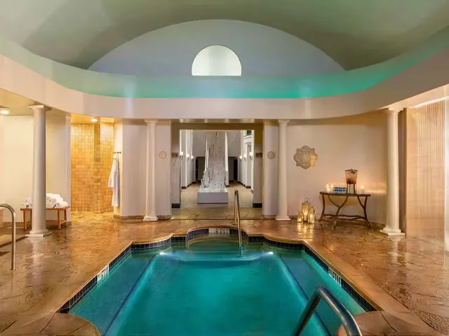 Indoor mineral pool with steam rising, decorated with pillars and soft lighting at Fairmont Sonoma Mission Inn & Spa in Sonoma, California.