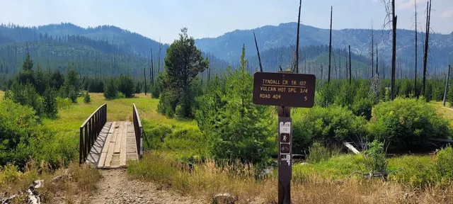 Signpost on the trail towards vulcan hot springs with mountain valley views