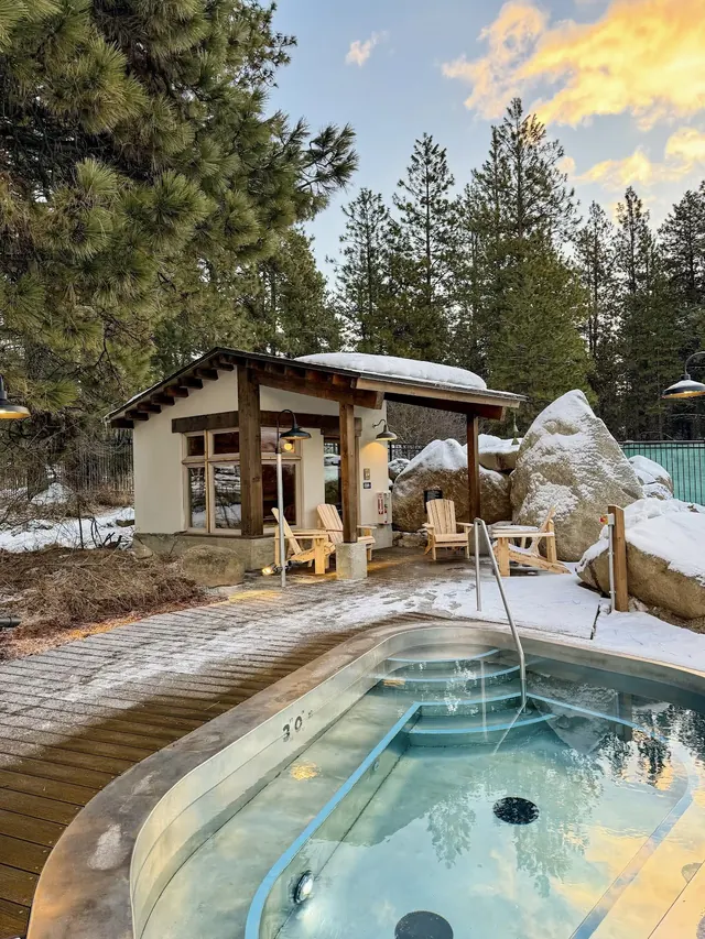The Springs outdoor spa pool surrounded by snow-covered rocks and pine trees near Leavenworth Washington.