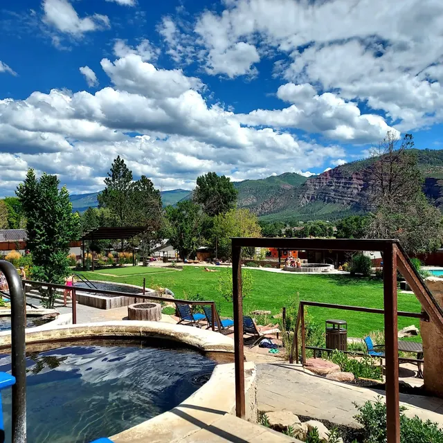 Outdoor spa pool and lush green grounds under a partly cloudy sky at Durango Hot Springs near Durango, Colorado, United States.