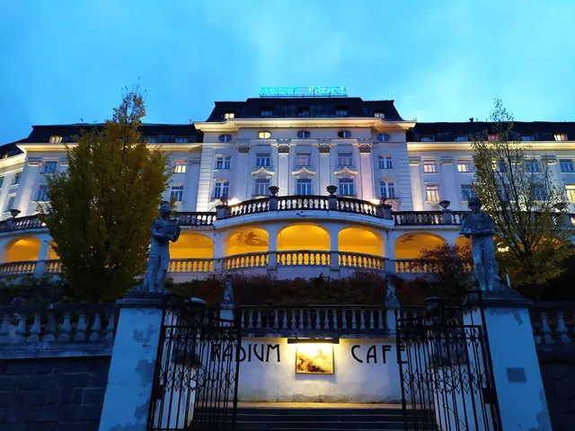 Evening exterior of Radium Palace Spa & Wellness building in Jachymov with illuminated arches and statues under a dark sky.