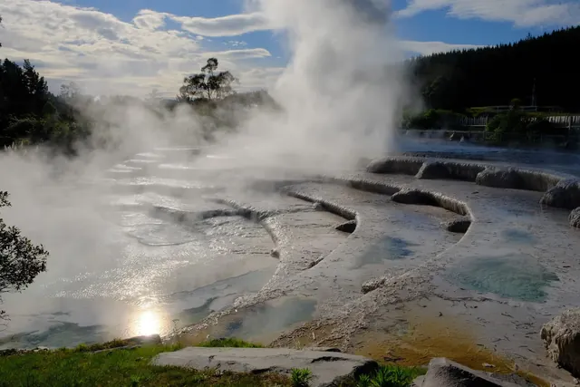 Multiple hot spring pools with steam rising and a wooden bridge at Wairakei Terraces near Taupō new-zealand.