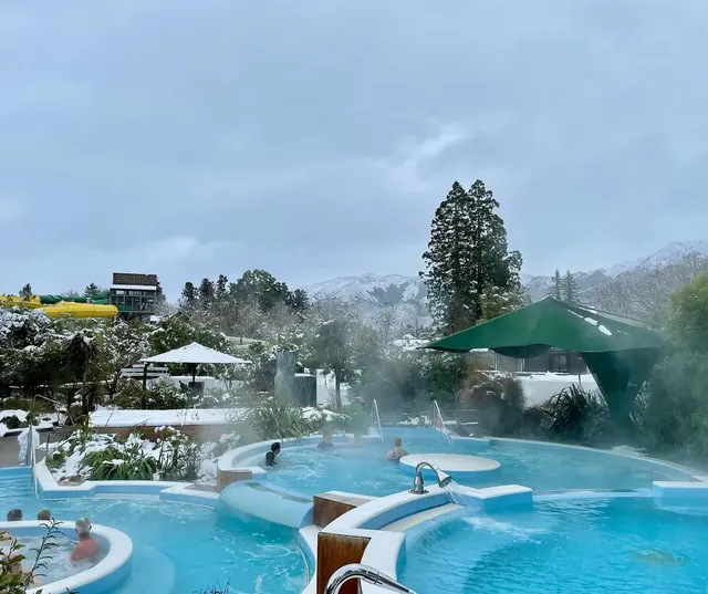 Hanmer Springs Thermal Pools & Spa features multiple steaming hot spring pools with snow-capped mountains in the background near Hanmer Spr.