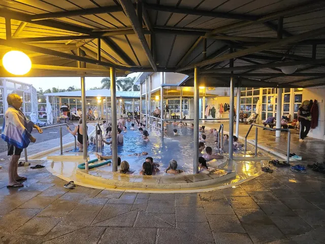 Indoor hot spring pool with many people soaking under a roof structure at Termas Villa Elisa near Villa Elisa, Argentina.