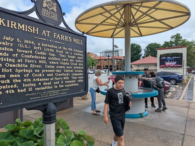 People gathered around the Hill Wheatley Plaza Jug Fountain hot spring in Hot Springs, Arkansas, with a historical marker nearby.