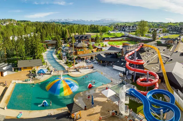 Outdoor pool at Thermal Baths Goracy Potok in Szaflary Poland with colorful dome play structure and twisting water slides.