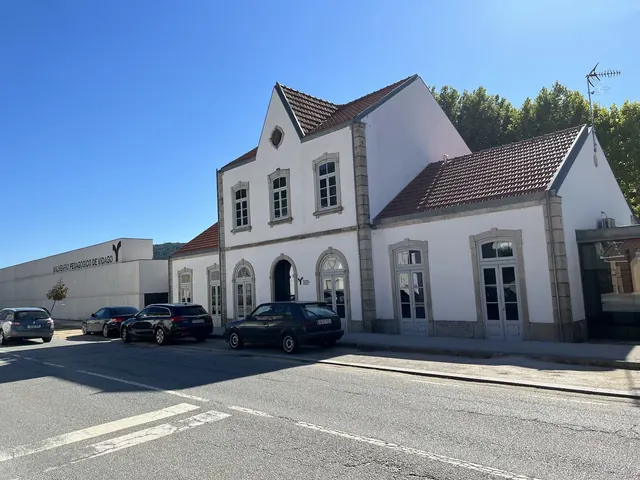 White historic building with tiled roof and cars parked in front at Balneario Pedagogico de Vidago, Vidago, Portugal.