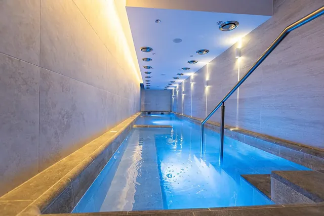 Narrow spa pool with waterfall jets and handrails in a tiled room at Thermal Aqua Park Persenk, Devin, Bulgaria.