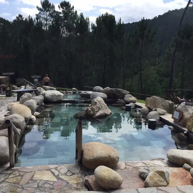 outdoor hot spring pools lined with rocks and with mountains in the background at termas de prixigueiro in spain